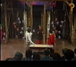 View from crowd of contestants stood around the table in front of an underwater backdrop