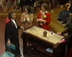 Person dressed up as a vampire around the table with the contestants