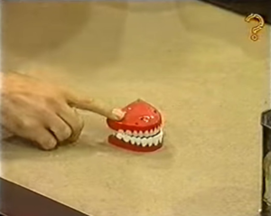 Finger touching a pair of toy teeth