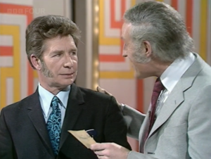 host looking at contestant while holding a card