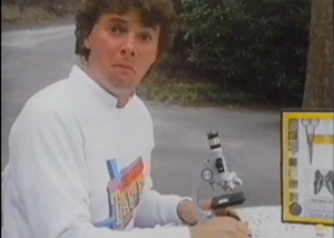 Student holding a microscope with a puzzled face