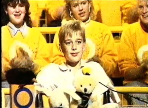 A young boy with stuffed animals with a microphone in front of him